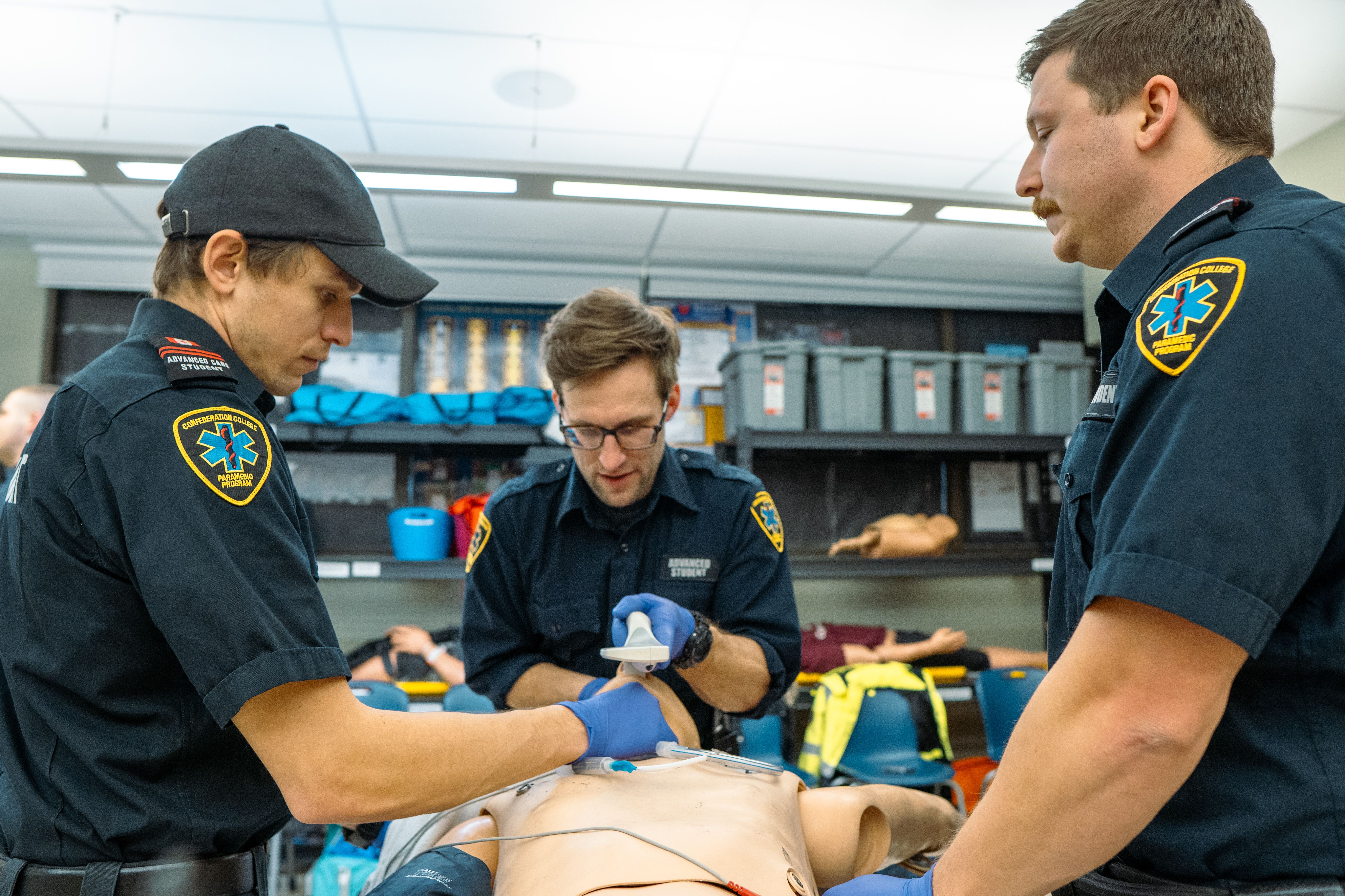Paramedic students practicing emergency procedures on a training manikin in a lab