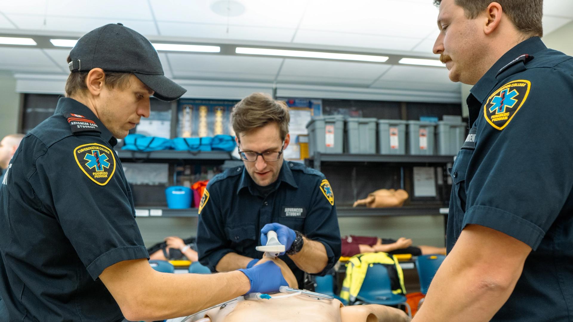 Paramedic students practicing emergency procedures on a training manikin in a lab