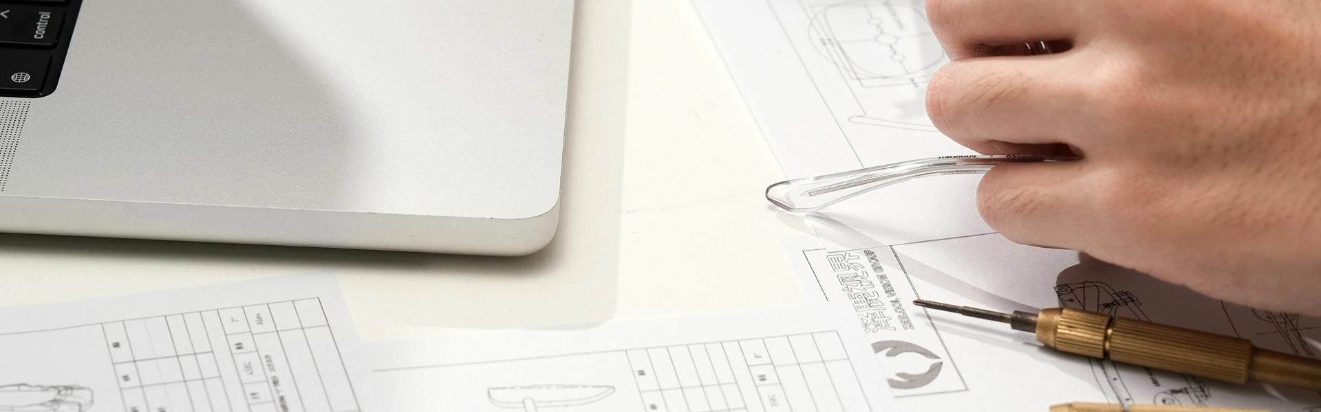 Student using precision measuring tools to review technical design drawings at a workstation