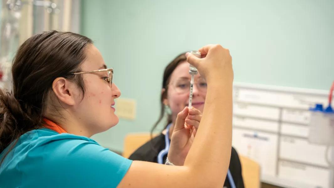 Nursing students preparing a syringe during skills practice