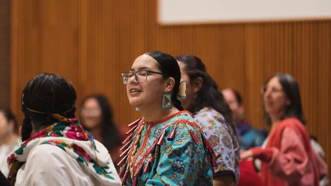 Participant wearing colorful traditional clothing during an indoor cultural event