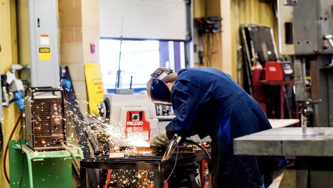Student grinding metal with sparks in a welding and fabrication lab