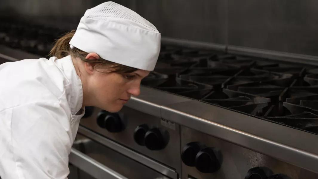 Culinary student checking settings on an industrial stove