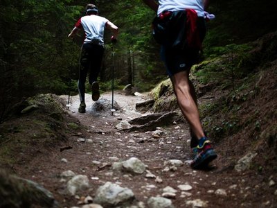 People trail running on a rocky forest path during an outdoor recreation activity