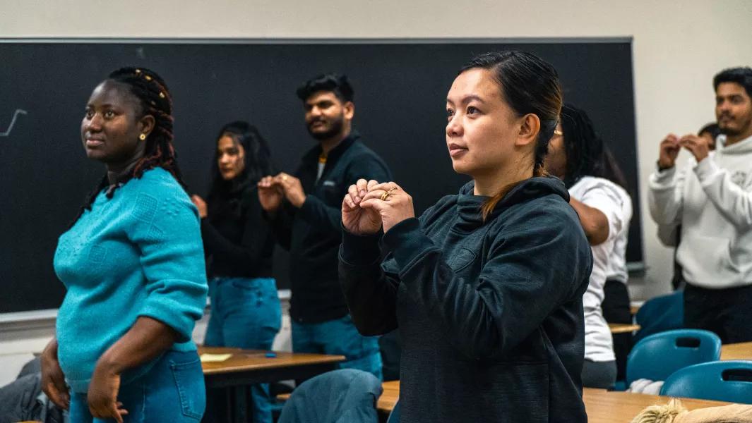 Students practicing hand-sign activities together in a classroom