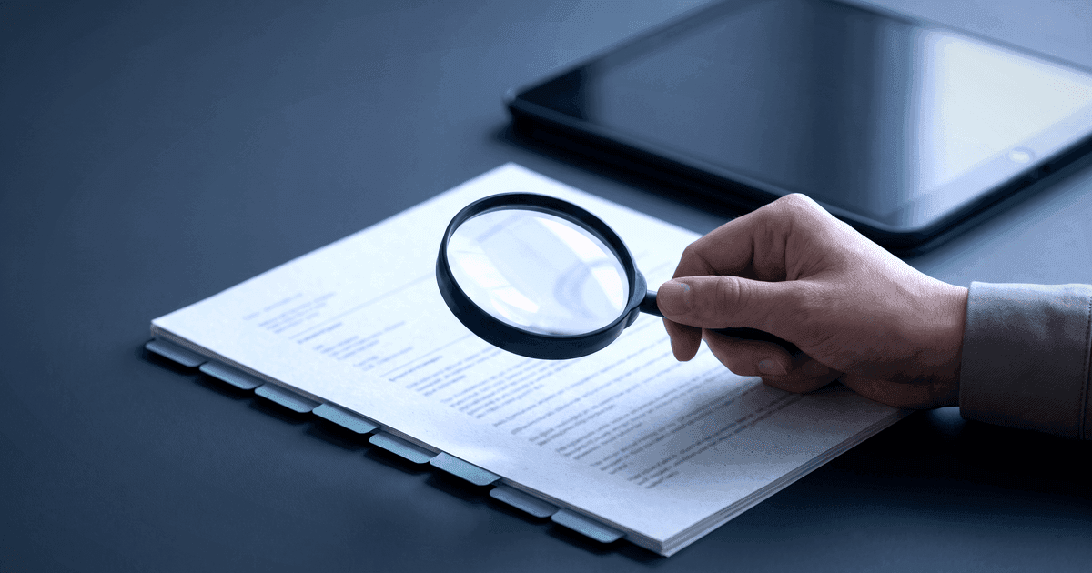 A person reviewing a structured document with a magnifying glass and checklist tabs