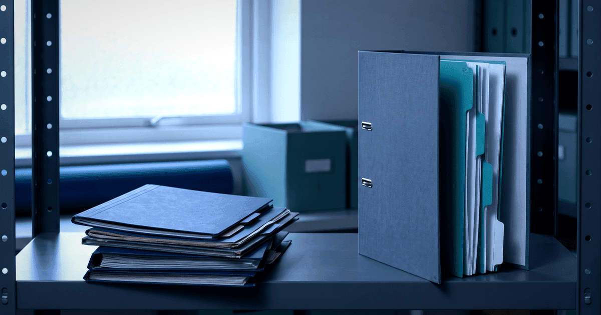 Scattered school record folders beside one organised profile binder with section dividers