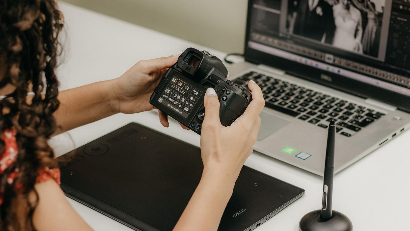 Photographer with a camera at a laptop, editing photos