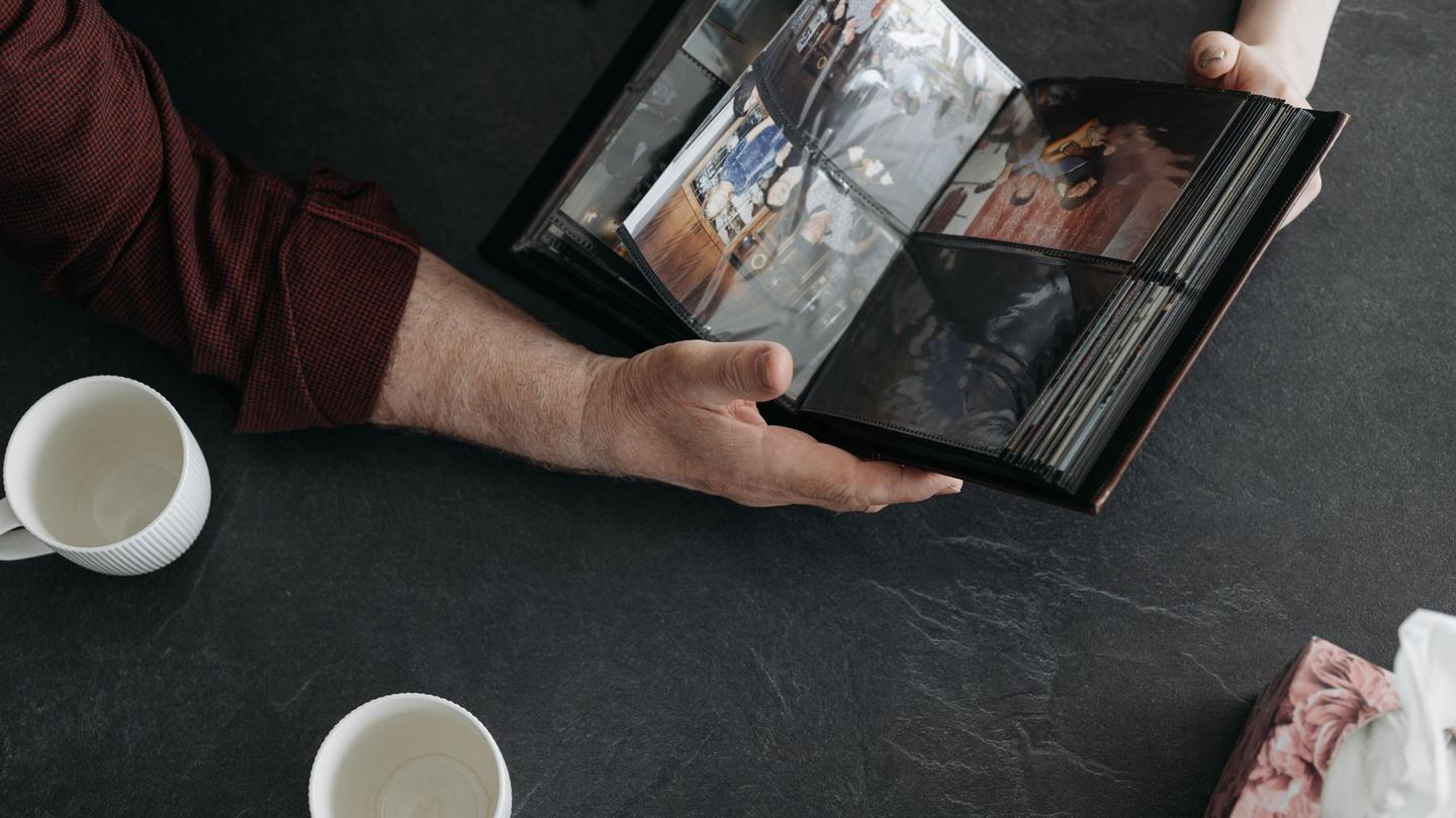 Hands holding an open wedding album on a table