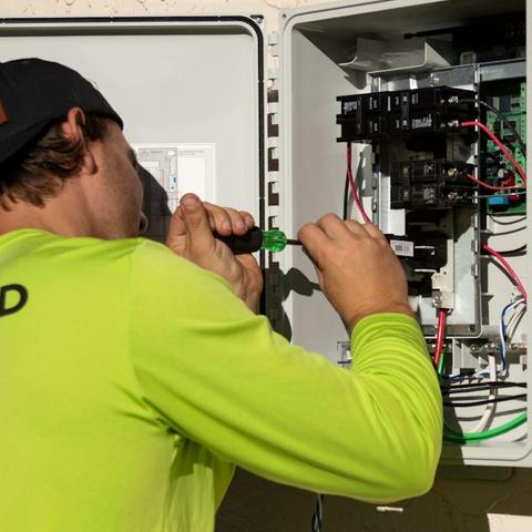 Tecnico al lavoro su un quadro elettrico aperto