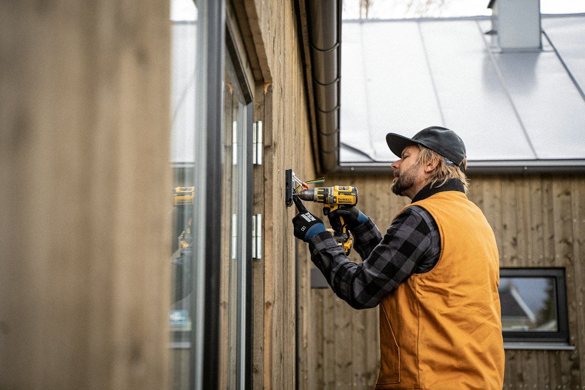 Elettricista al lavoro con il trapano su una parete in legno