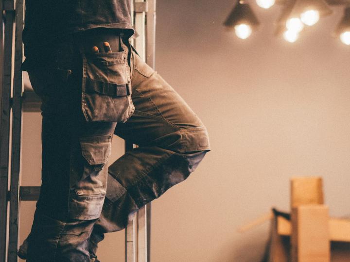 Elettricista su una scala durante il rifacimento di un impianto