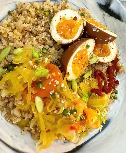 Two peeled and halved marinated jammy eggs over a bed of cauliflower rice. 