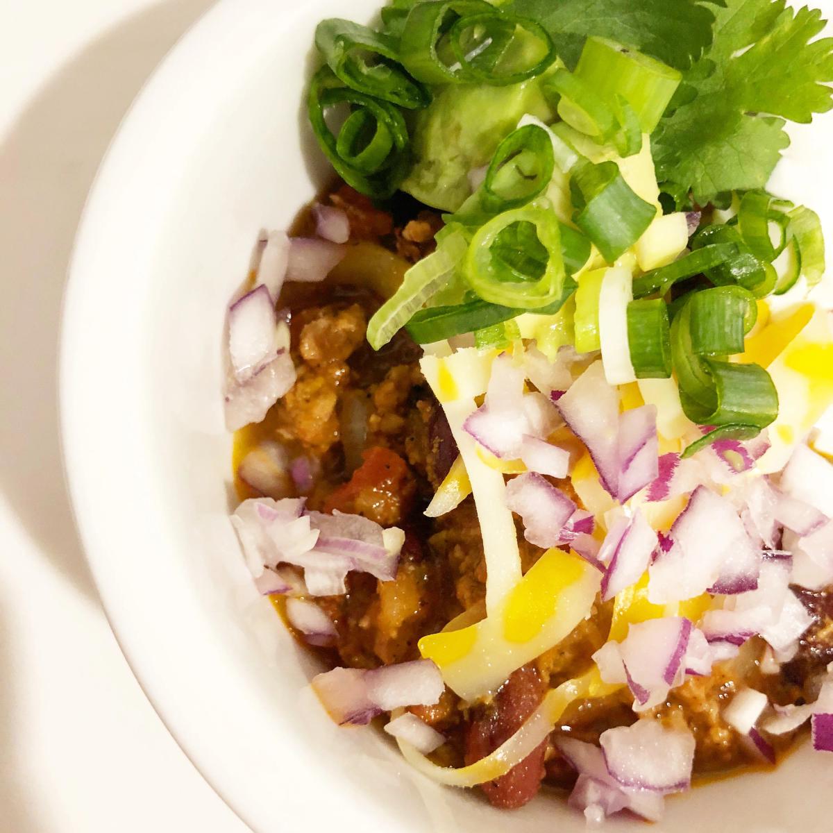 Chili with red onion, green onions, and beans