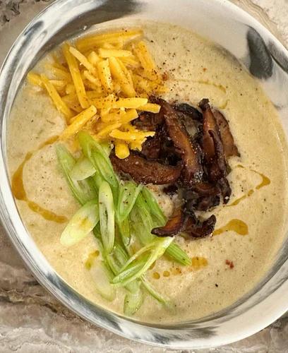 Bowl of hearty dairy-free leek soup topped with JF Shiitake Bacon, green onion and vegan cheddar.