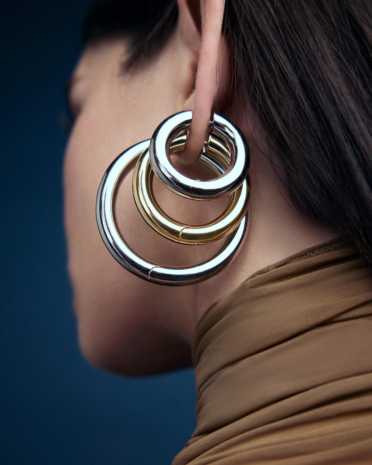 image of 3 different hoop earrings on a womens ear in silver and gold tones