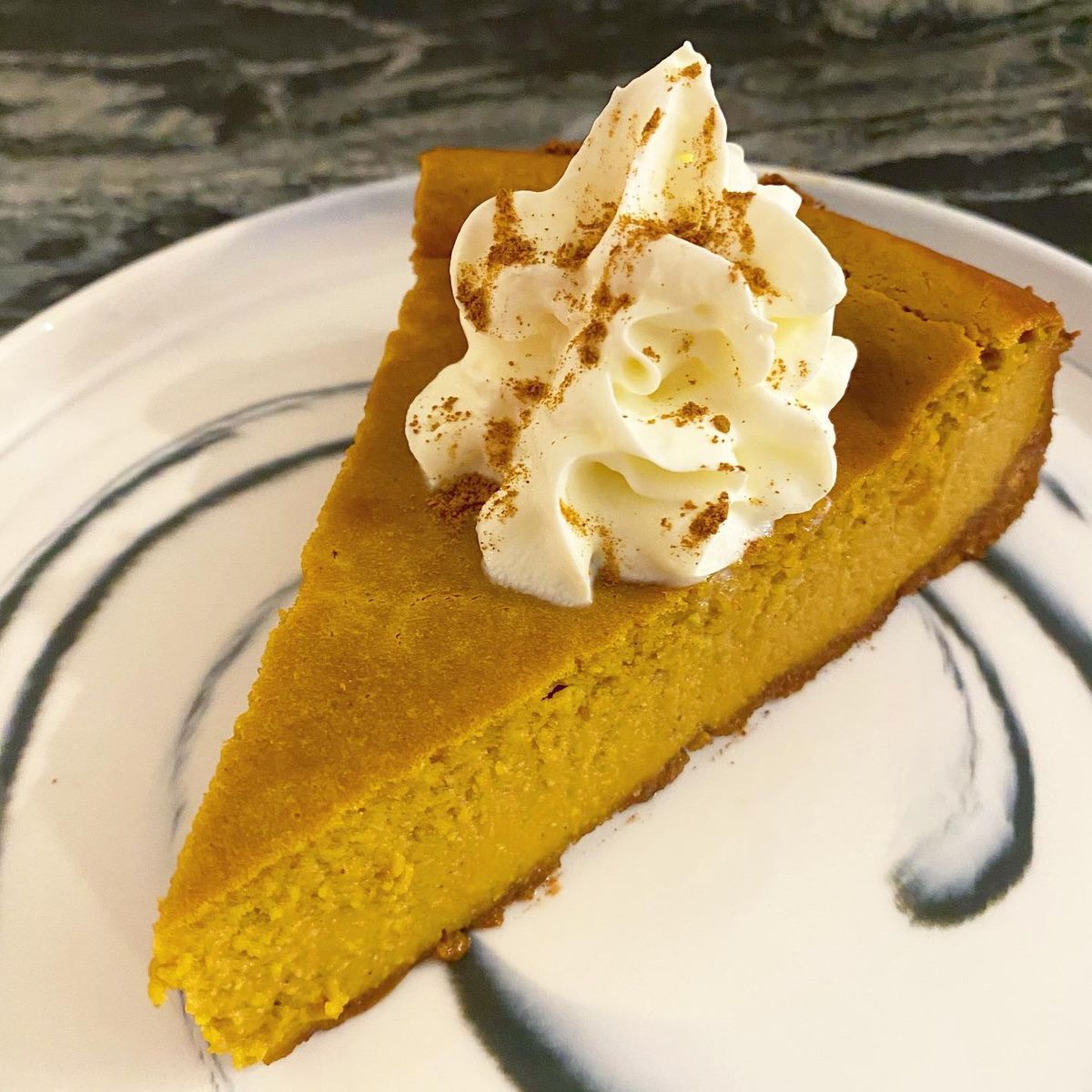 Slice of cheesecake made of pumpkin with cream on top