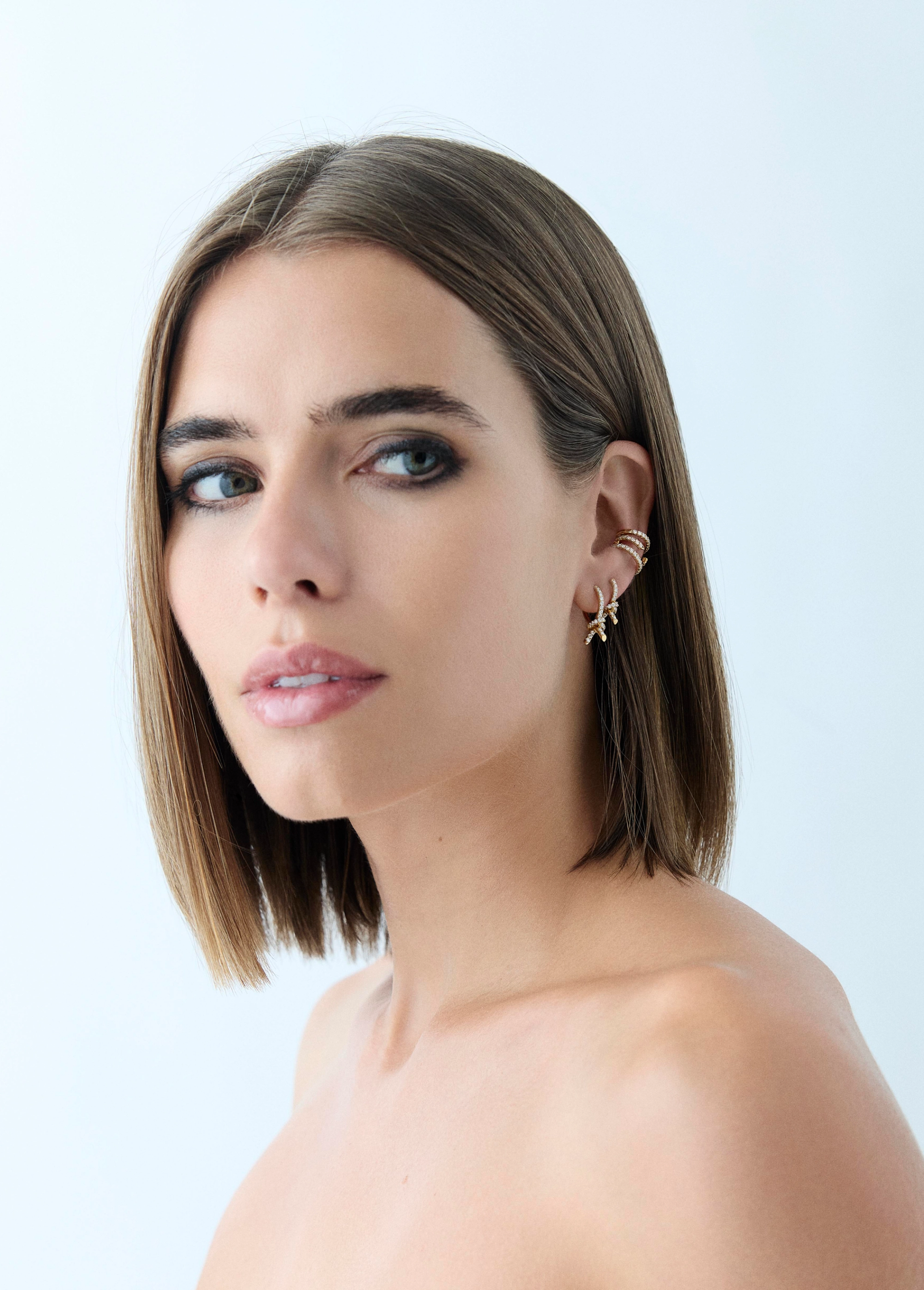 Model in lightweight gold shell earrings on a blue background