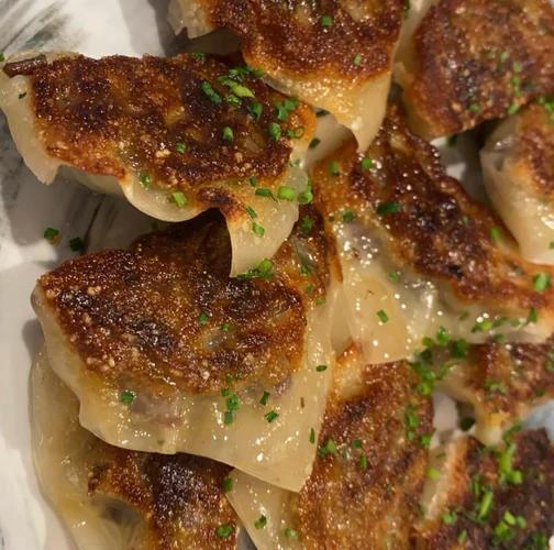 Plate of crispy pan seared potstickers garnished with chives.