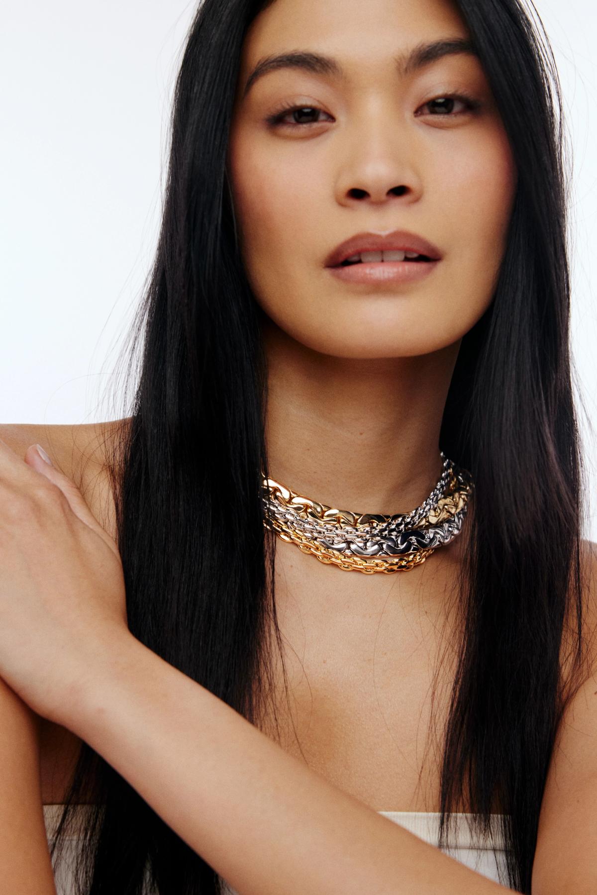 woman wearring different colour gold and silver toned chain necklaces