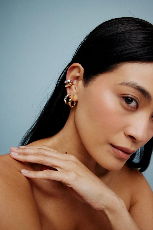 woman wearing election of earrings and placing her hand across her shoulder 