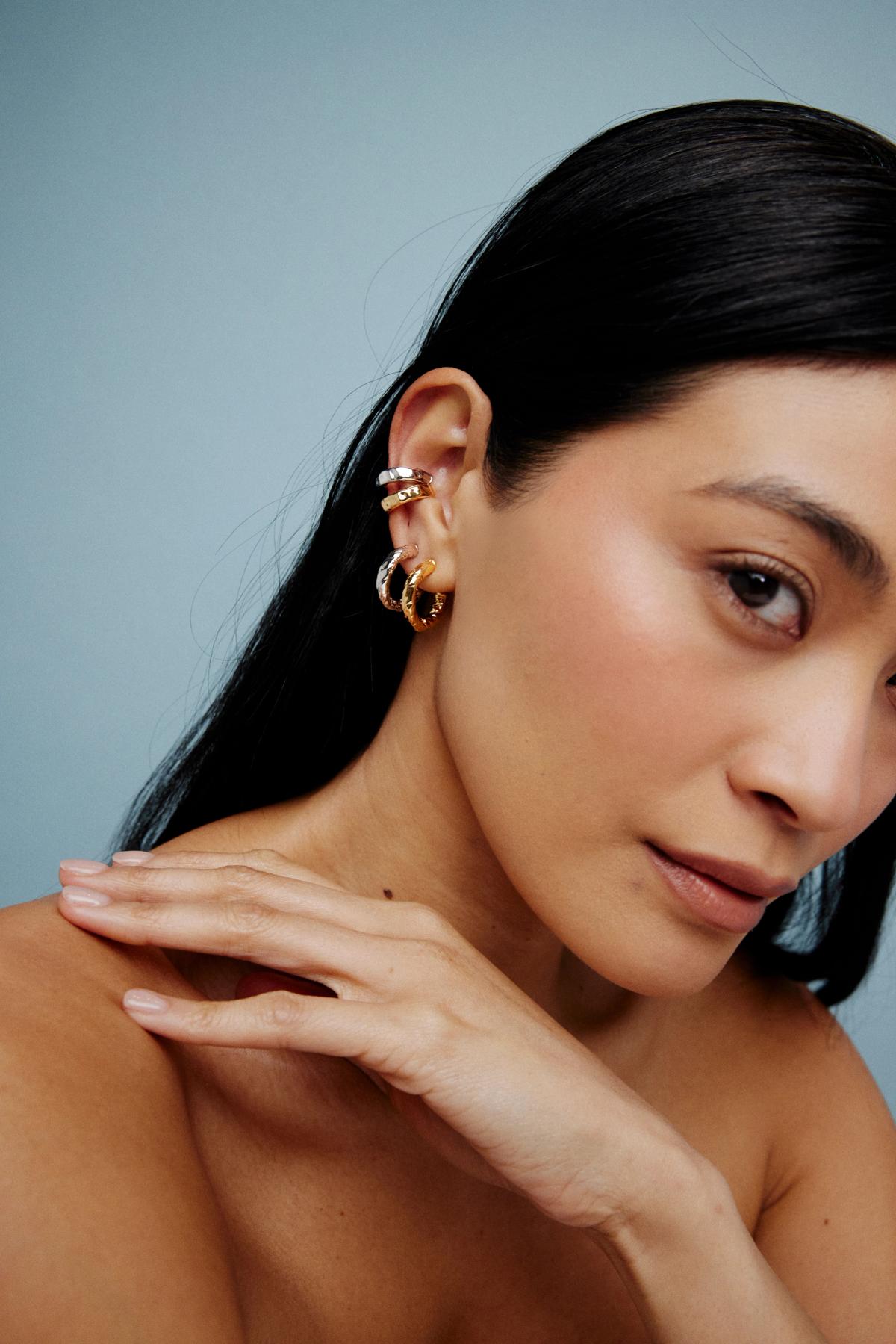 woman wearing election of earrings and placing her hand across her shoulder