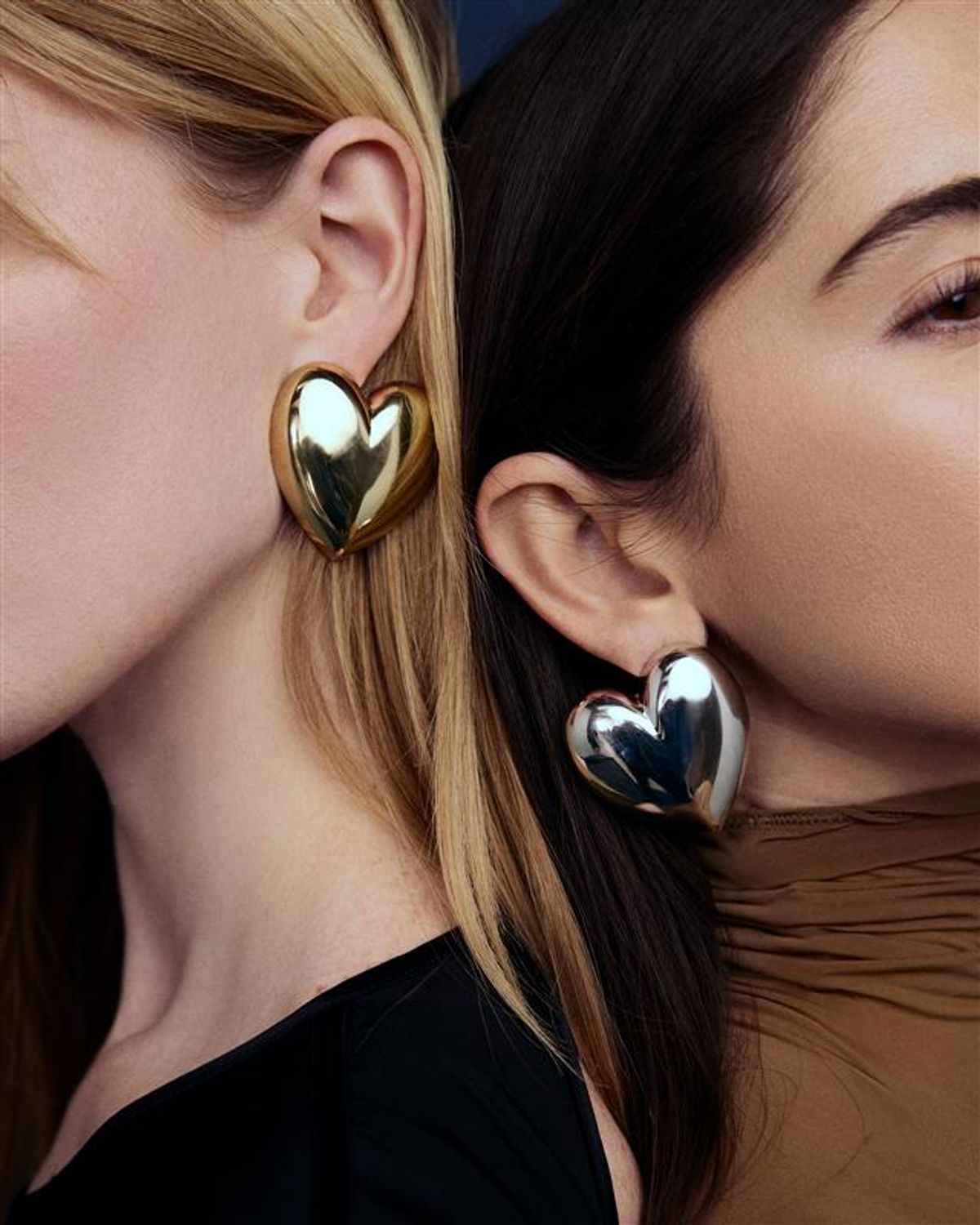 two women back to back with different color heart earrings on