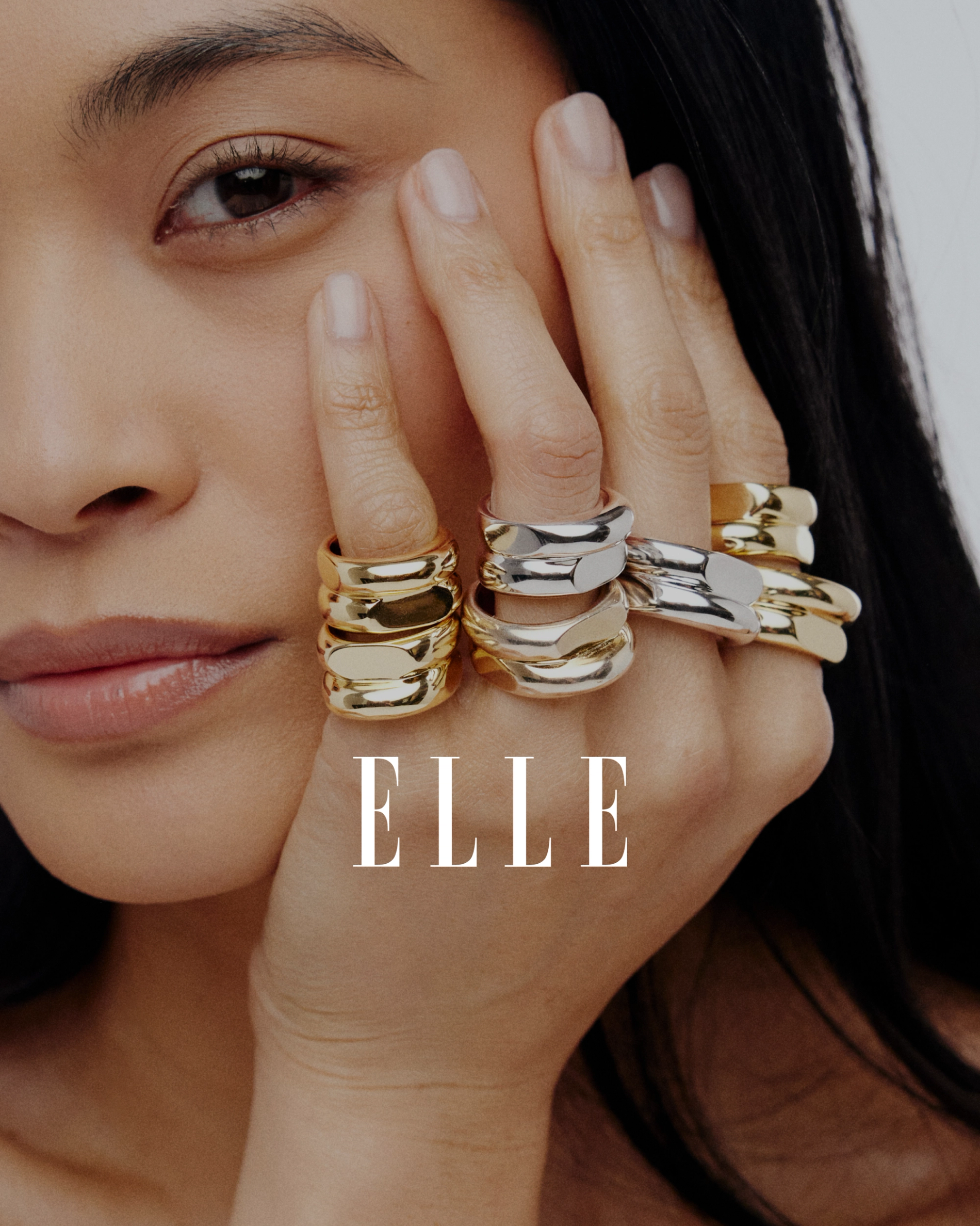 model with her hand on her face and a stacked silver and gold rings