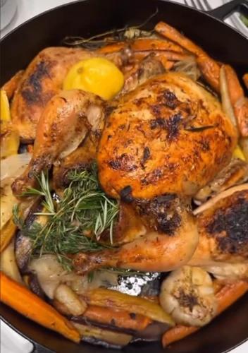 Roasted chicken with carrots, potatoes, onion, lemon, sage and thyme in a cast iron. 