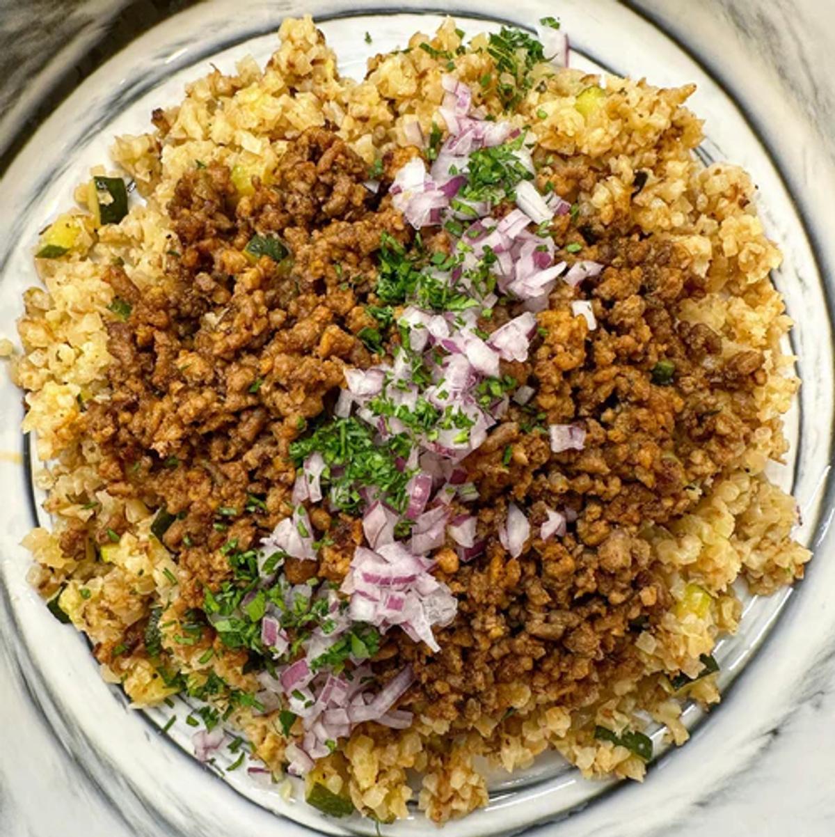 Sautéed ground pork over cauliflower rice and topped with chopped red onion, parsley, and vegan cheddar. 