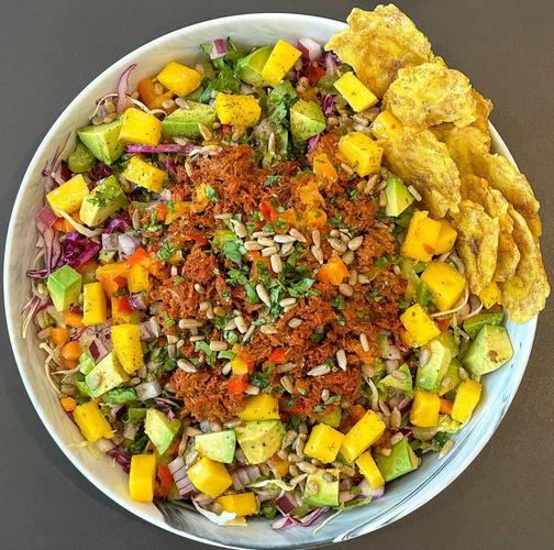 Tropical salad packed with romaine, green and purple cabbage, celery, avocado, mango, carrot, red onion, banana pepper, raw sunflower seeds, cilantro and chorizo tuna.
