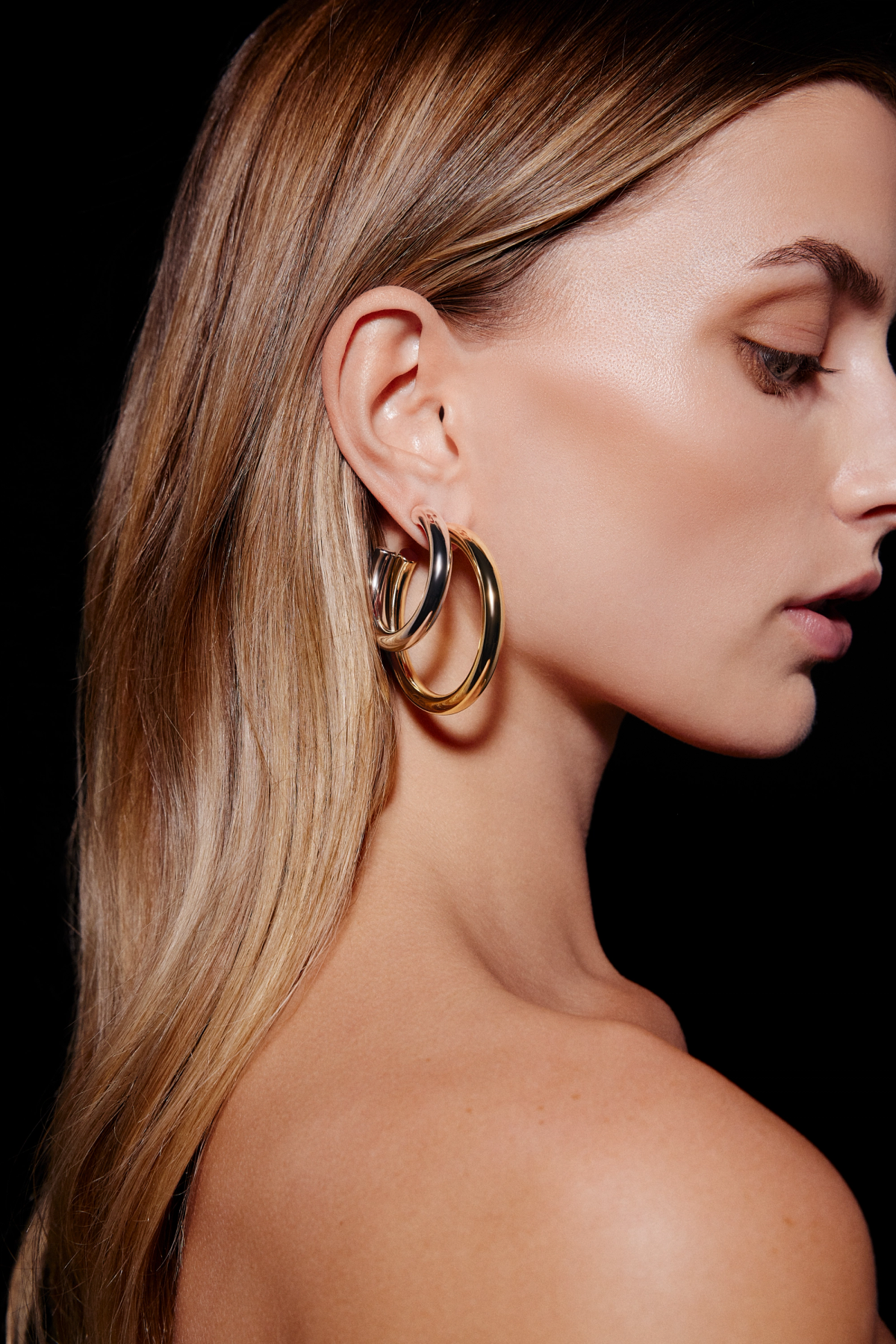 woman wearing differnet toned metal hoop earrings