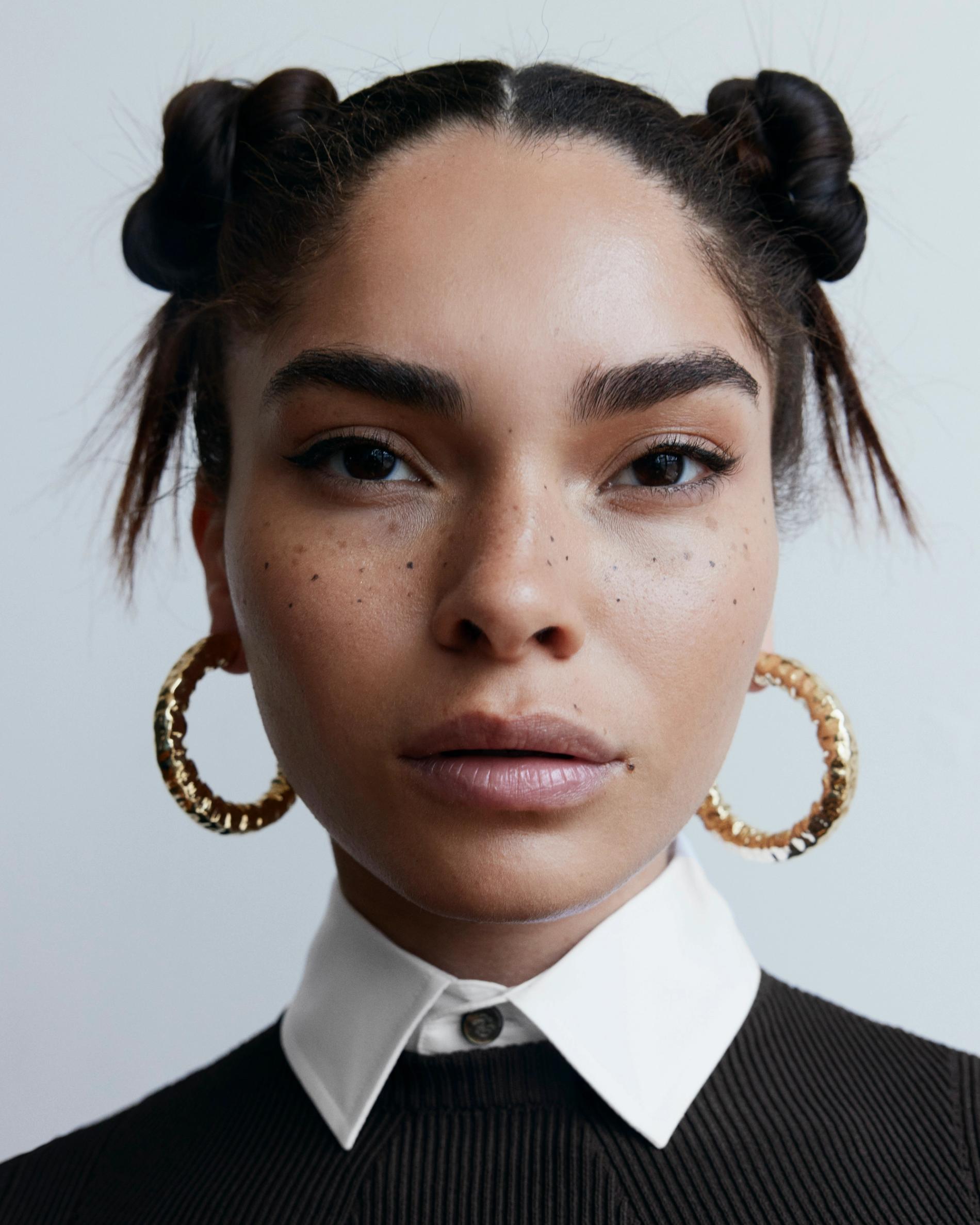 Image of a model facing the camera wearing medium sized thick gold hoops.