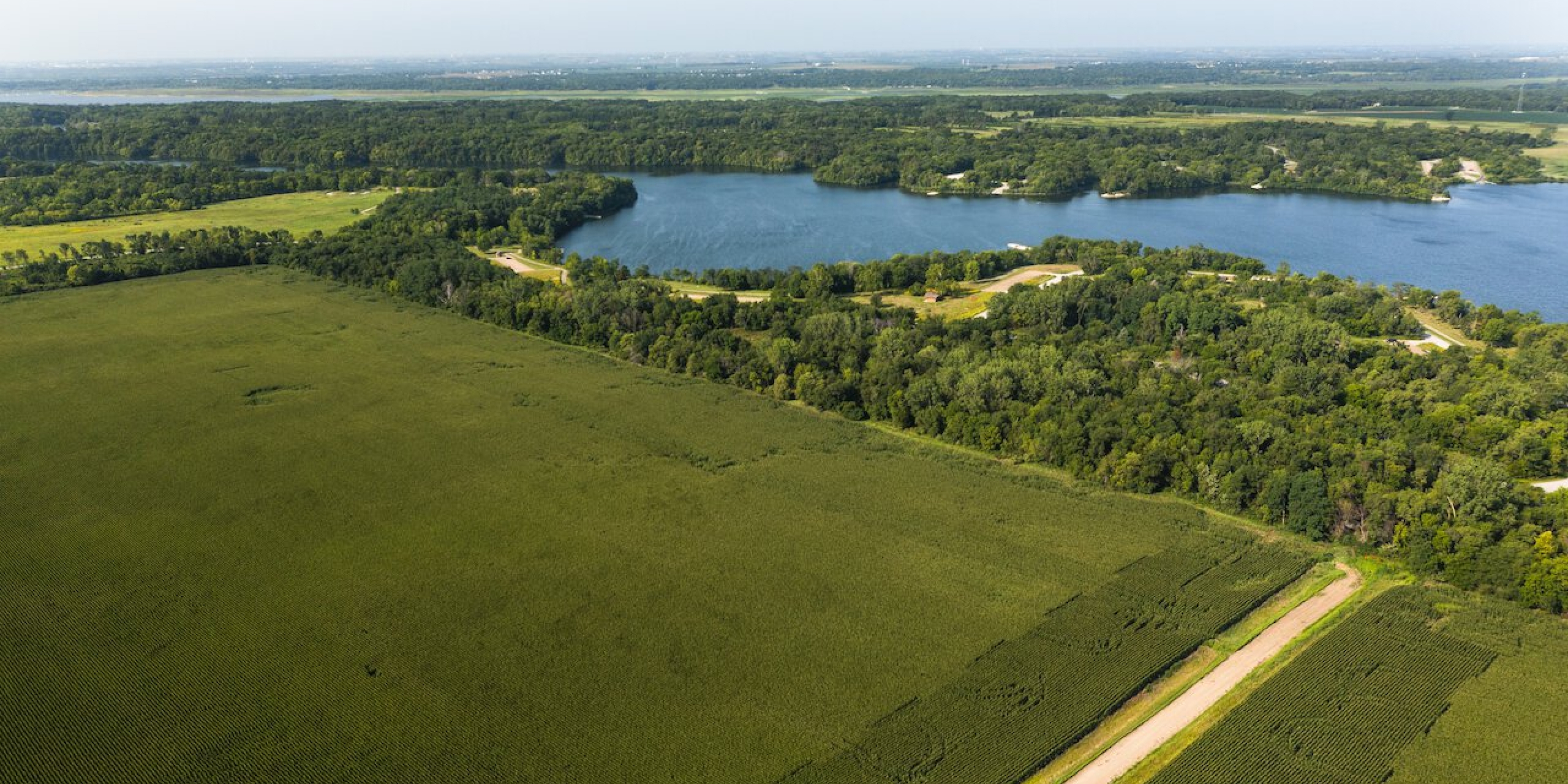 Aerial photography of a lush green field nearby a lake