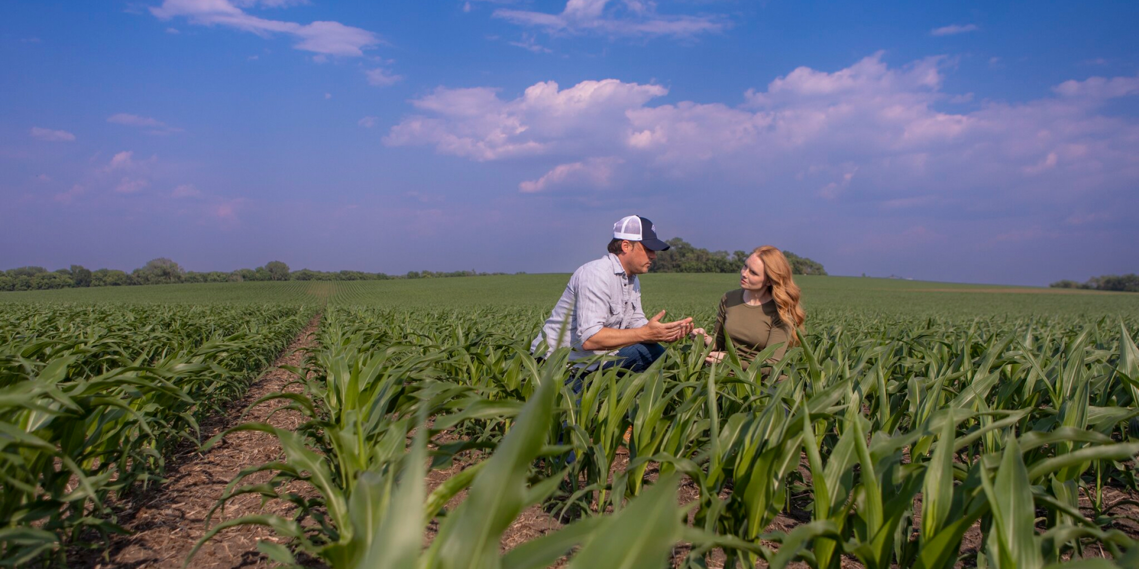 Farmer and Rep Kneeling and Speaking in a Corn Field