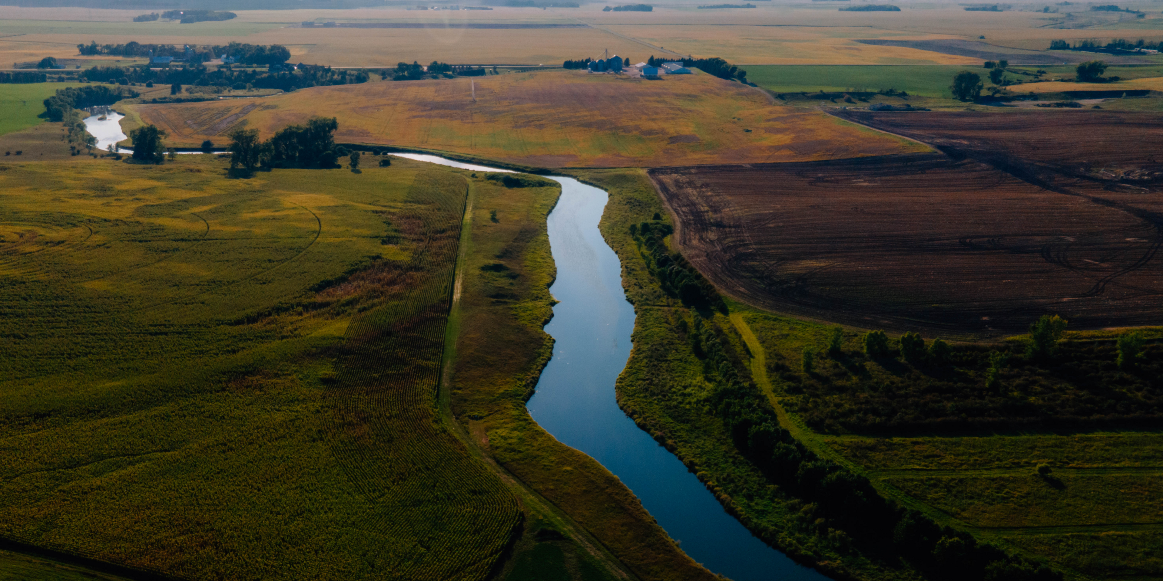 Aerial photo of a lush green field with a stream running through