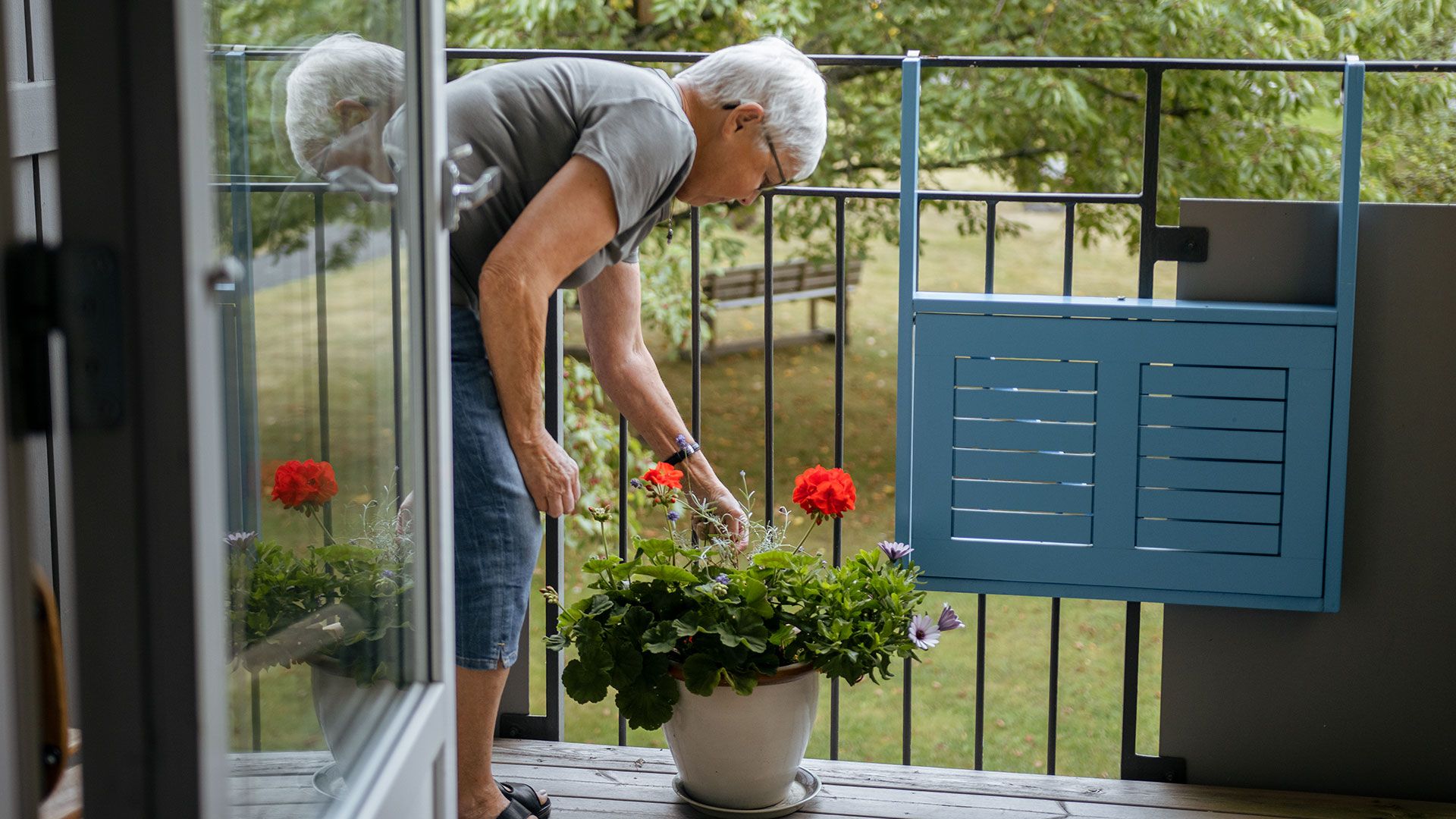 En kvinna som pysslar om sina blommar på balkongen