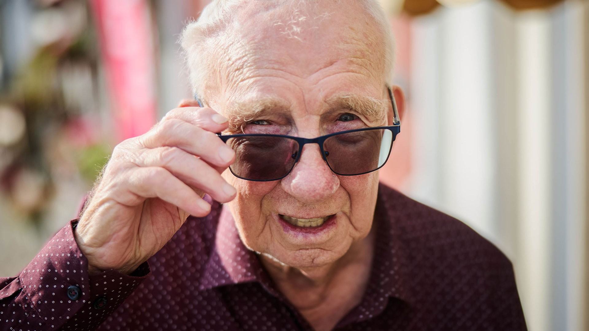 Äldre person som lyfter på glasögonen