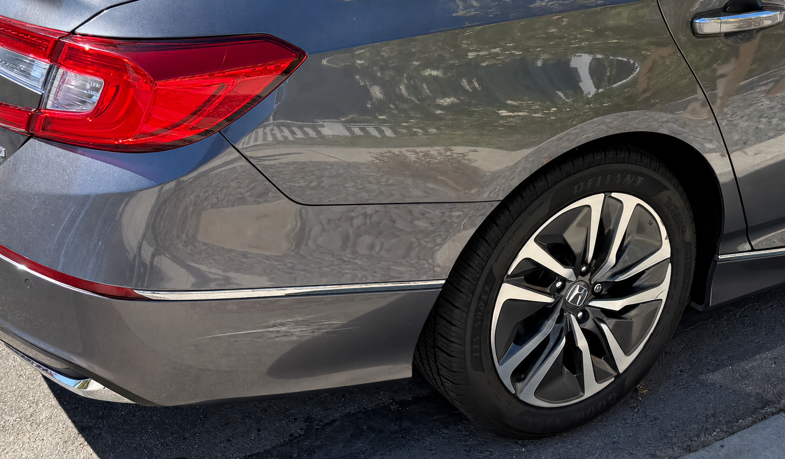 Scratches below the chrome trim on the Honda Accord Hybrid's rear bumper before correction
