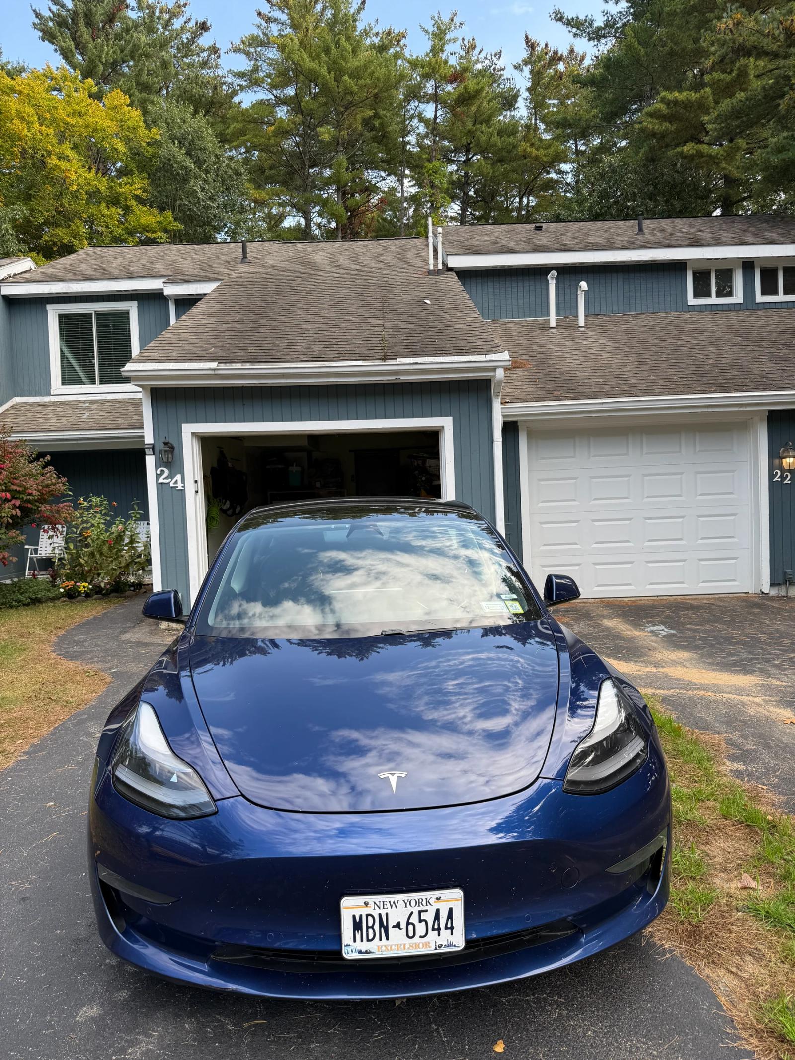 Front view of the blue Tesla Model 3 showing the finished hood, bumper and headlights