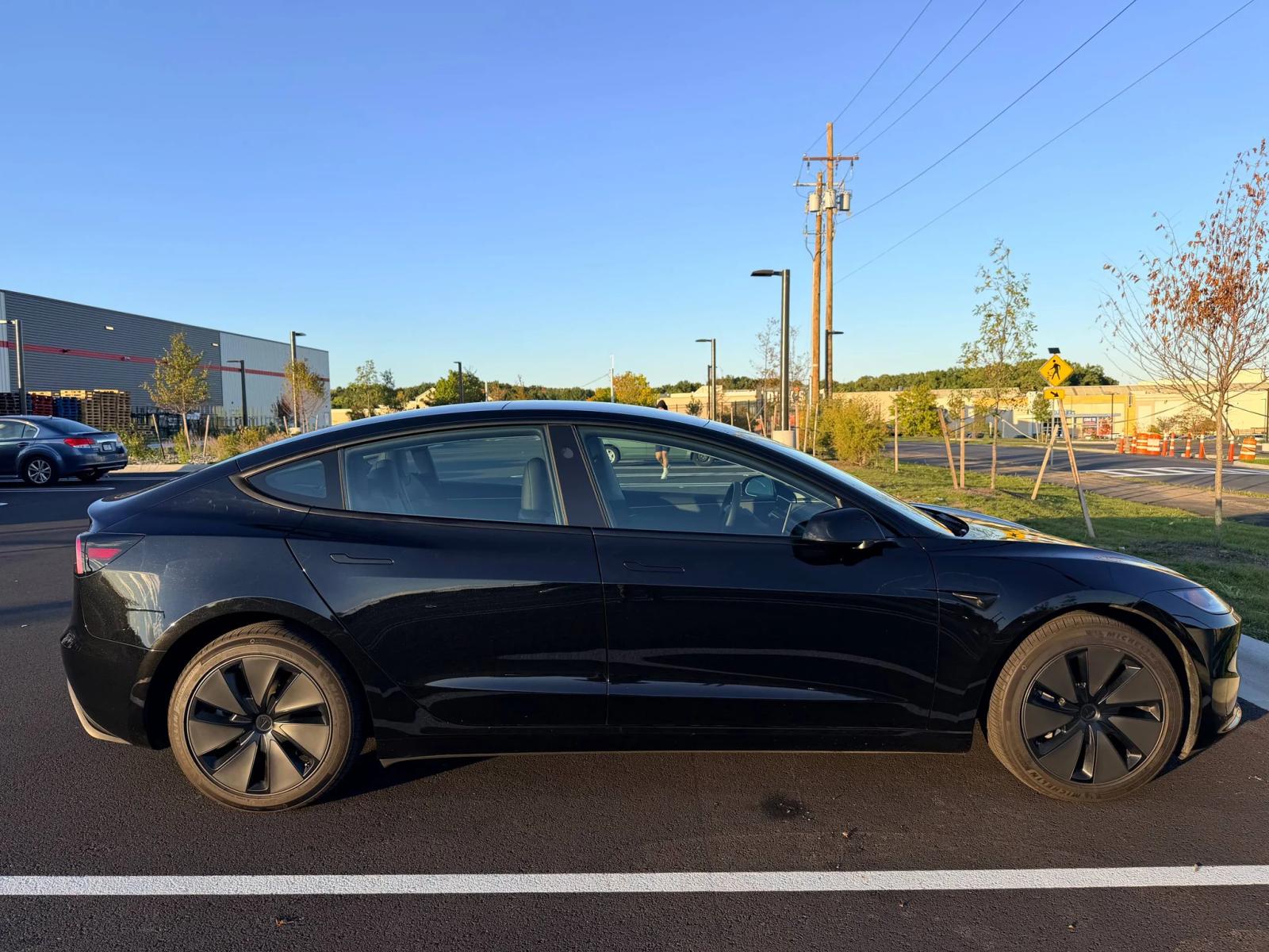 Side profile of a black Tesla with reflections along the doors.
