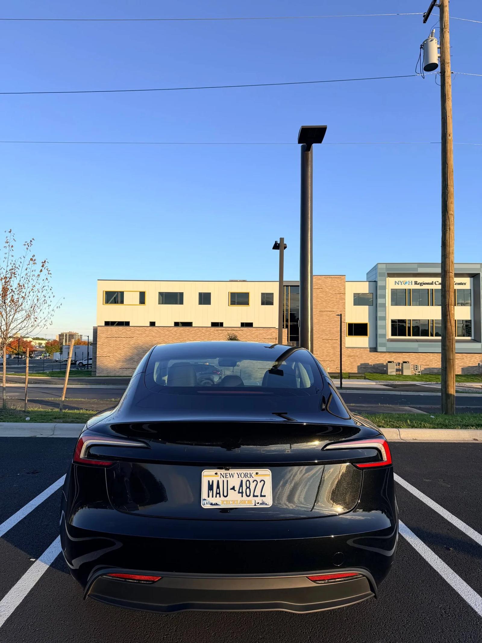 Full rear view of a black Tesla parked outdoors.