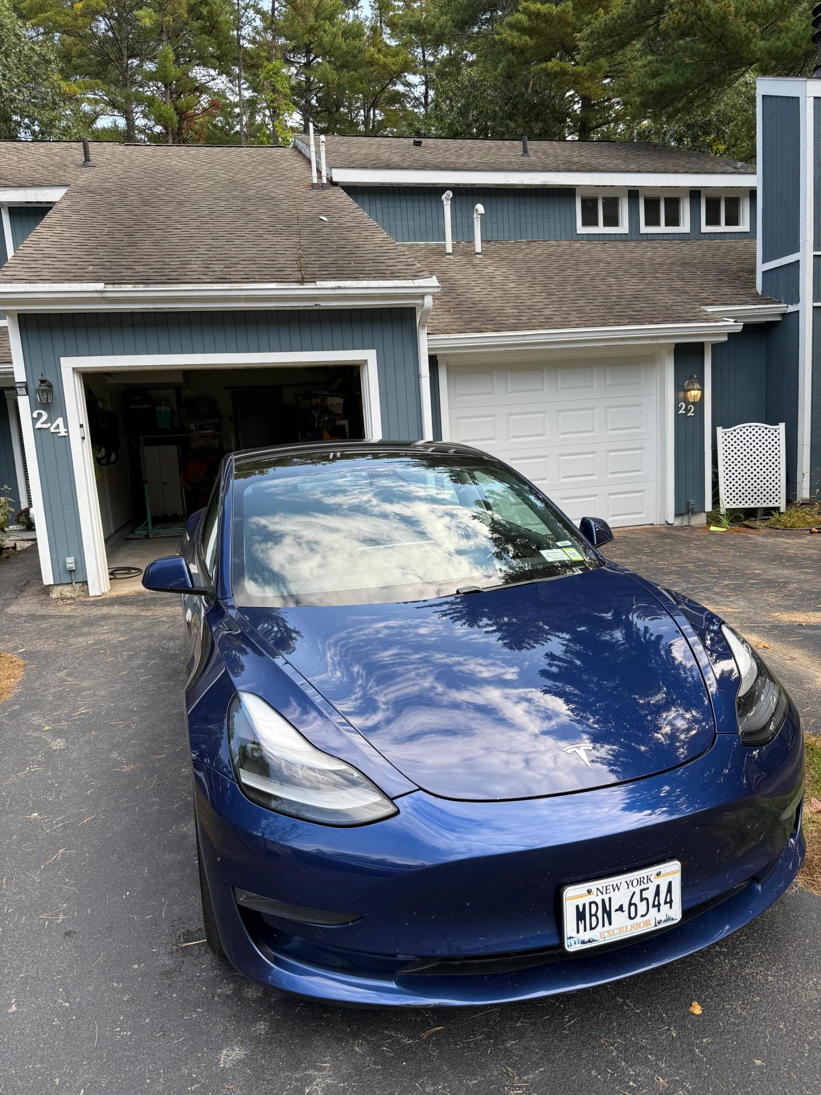 Reflections on the hood and front fender of the finished blue Tesla Model 3