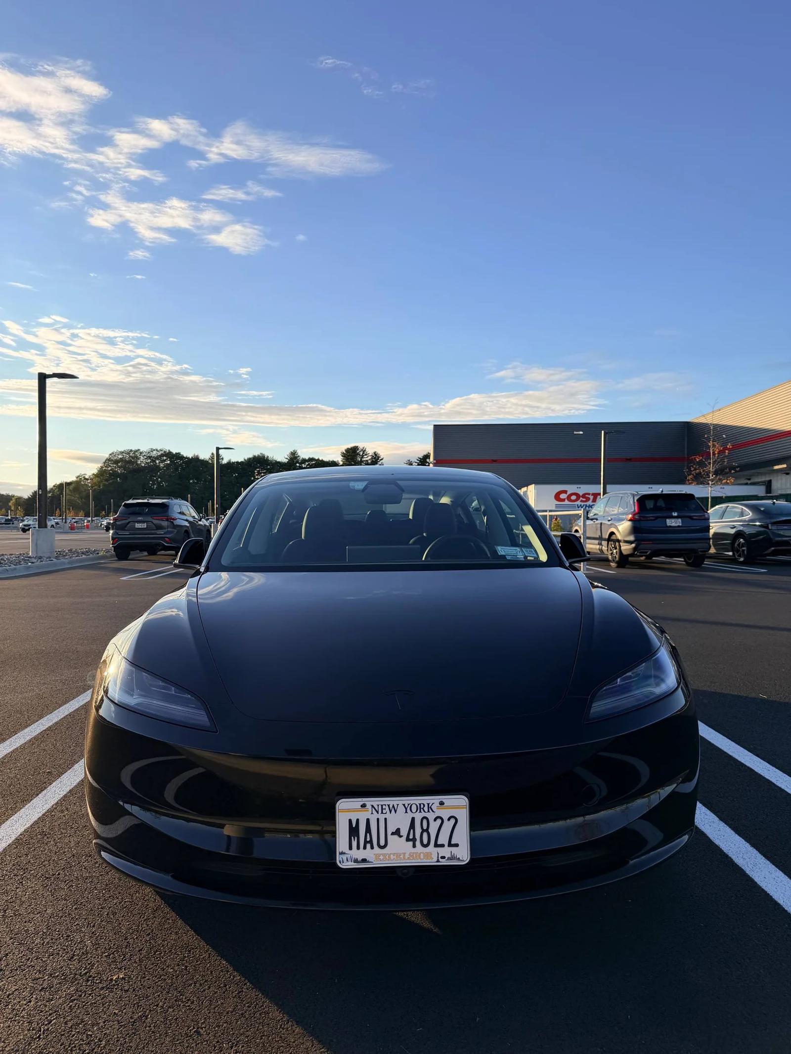 Front view of a black Tesla showing the hood, headlights and bumper.