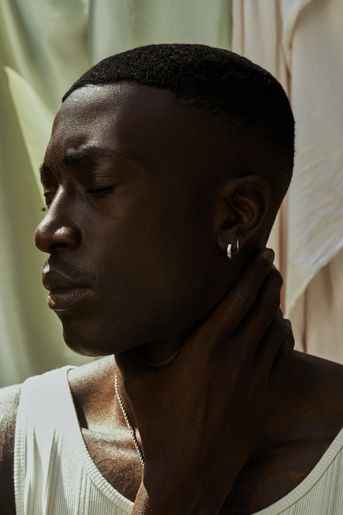 Black man holds his neck, against a serene backdrop