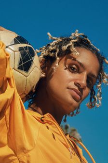 Young woman in yellow sweatshirt is holding soccer ball