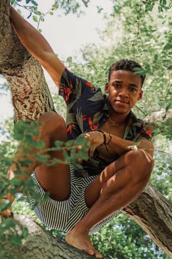 Young black man is climbing and sitting in a tree