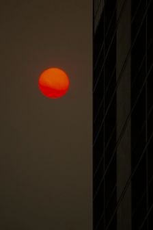 Dark sky with orange red moon next to the side of a cityscape