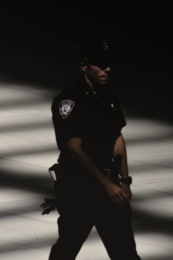 Police man standing faced in darkness