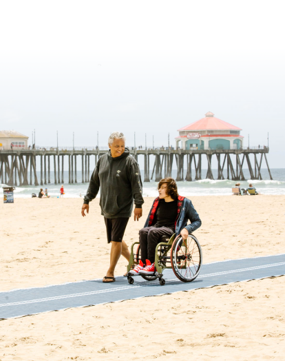 a father and his son at weelchair walking trought the beach